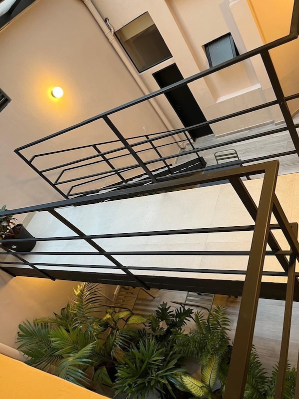 A modern interior with a metal staircase, potted plants, and a light fixture.