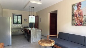 Une cuisine moderne avec un coin bar, une table à manger et un canapé gris.
