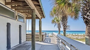 A wooden boardwalk leading to a beach with palm trees and a clear view of the ocean. - The Brinley House:Steps from Beach/Pool/Bikes etc. (Destin)