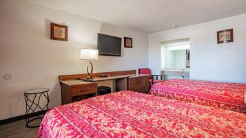 A hotel room with two beds, a desk, a chair, a TV, and a small table.