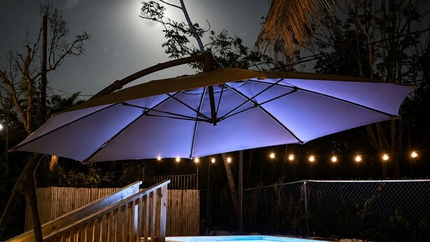 A backyard with a swimming pool, a wooden deck with stairs, and an umbrella.