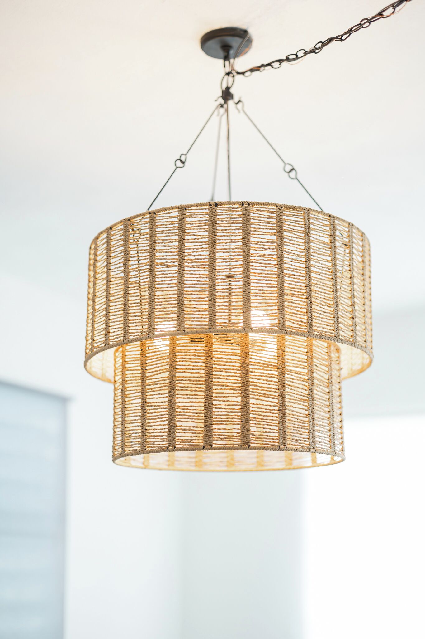A wicker pendant light fixture with a chain mount, hanging from a ceiling.