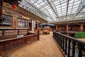A traditional wooden structure with a glass ceiling, wooden benches, and a railing. - Songjing Bieyuan Homestay (Shangri-La Ganden Sumtseling Monastery) (Shangri-La)