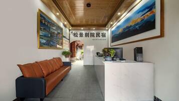A reception area with a reception desk, a sofa, and framed artwork on the walls.