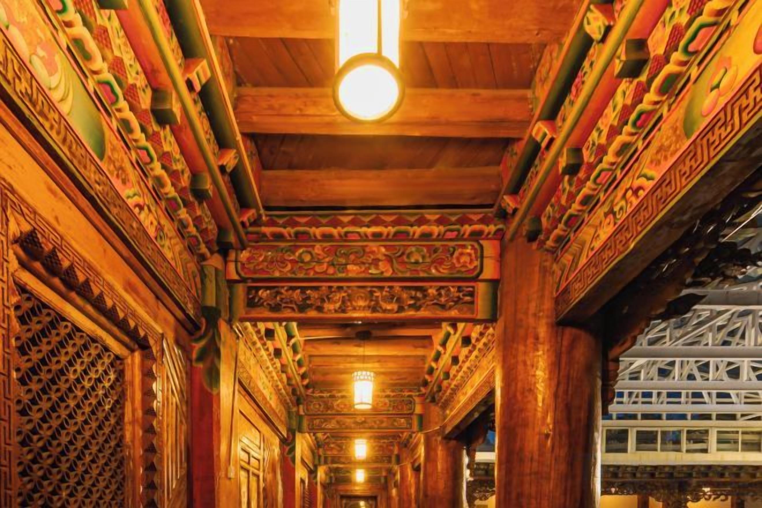 A corridor with ornate wooden carvings and a hanging light fixture.