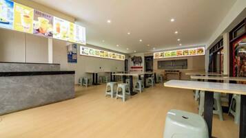 A restaurant with a counter, tables, and stools.