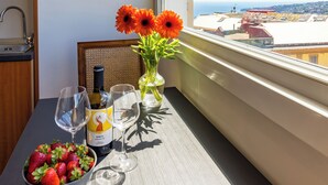 A balcony with a table set for two, featuring a bowl of strawberries, a bottle of wine, and two glasses. - Chiave di Fuga - Tripla Superior - Camera 2 (Naples)