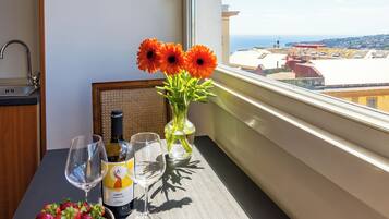Un balcon avec une table dressée pour deux personnes, agrémentée d’un saladier de fraises, d’une bouteille de vin et de deux verres.