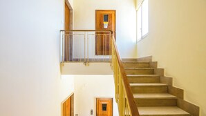 A staircase with a wooden handrail and a metal railing, leading to a landing with a door.
