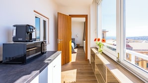 A modern kitchen with a coffee machine, a wooden door leading to a bedroom, and a view of the city through large windows. - Chiave di Fuga - Doppia Superior -  Camera 4 (Naples)