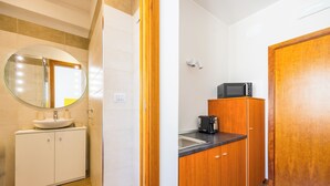 A compact kitchen with a sink, microwave, and wooden cabinets. - Chiave di Fuga - Singola Classic - Camera 1 (Naples)