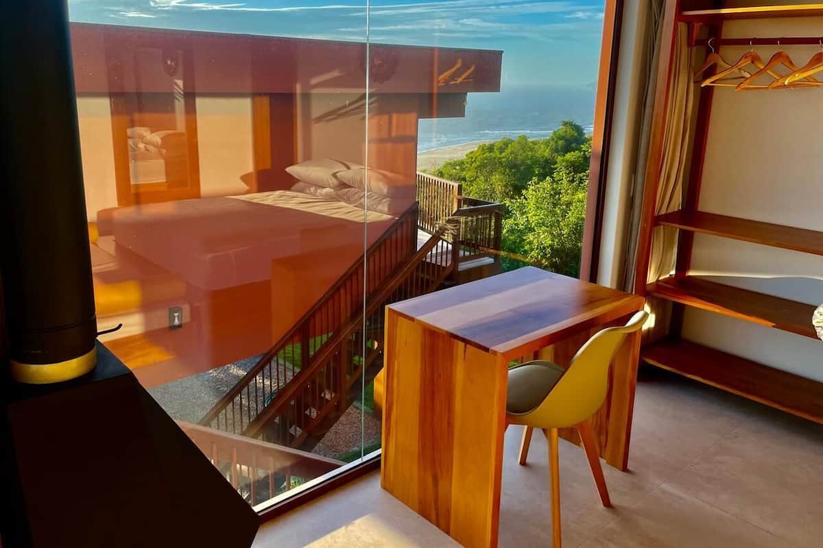 Une pièce moderne avec une grande fenêtre en verre, une table en bois et une chaise.