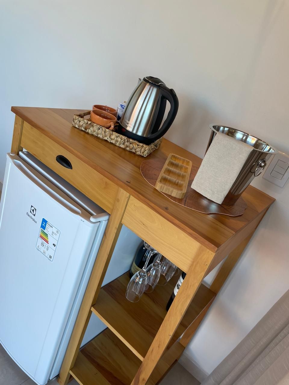 A compact kitchenette with a refrigerator, a kettle, and a small sink.