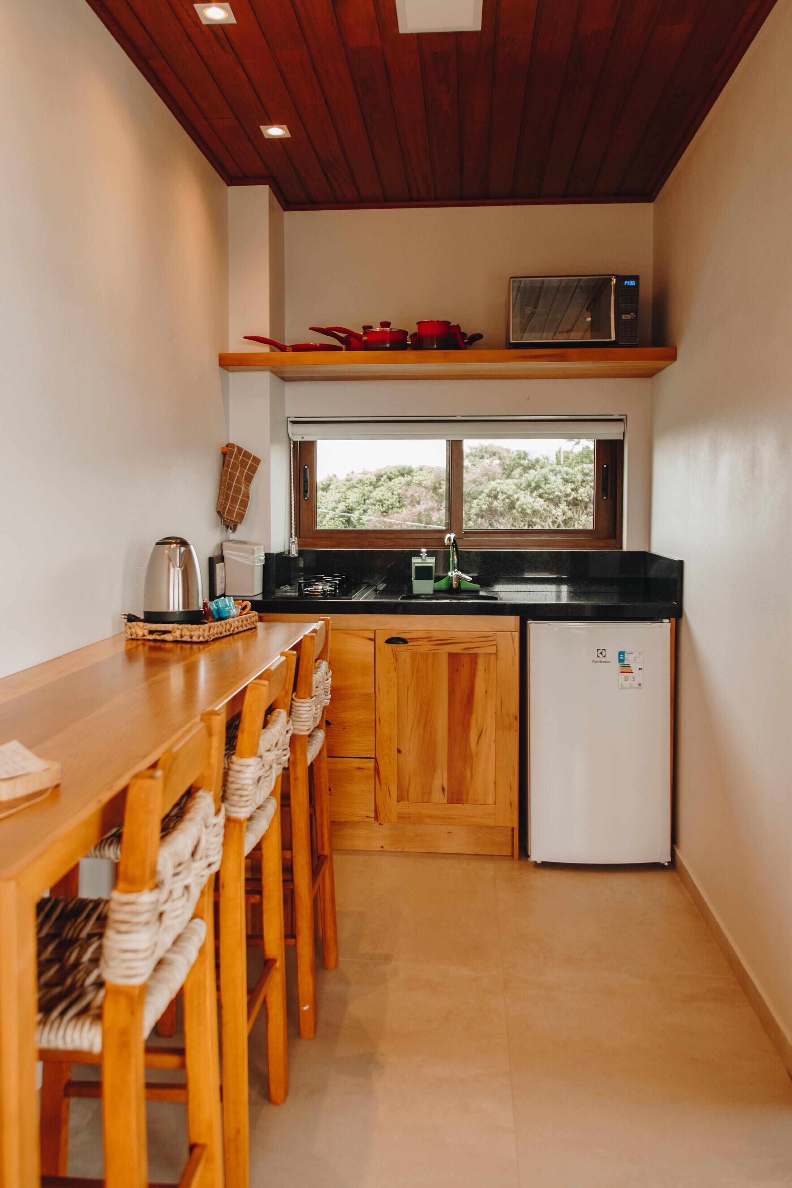A compact kitchen with wooden cabinets, a black countertop, and a white refrigerator.