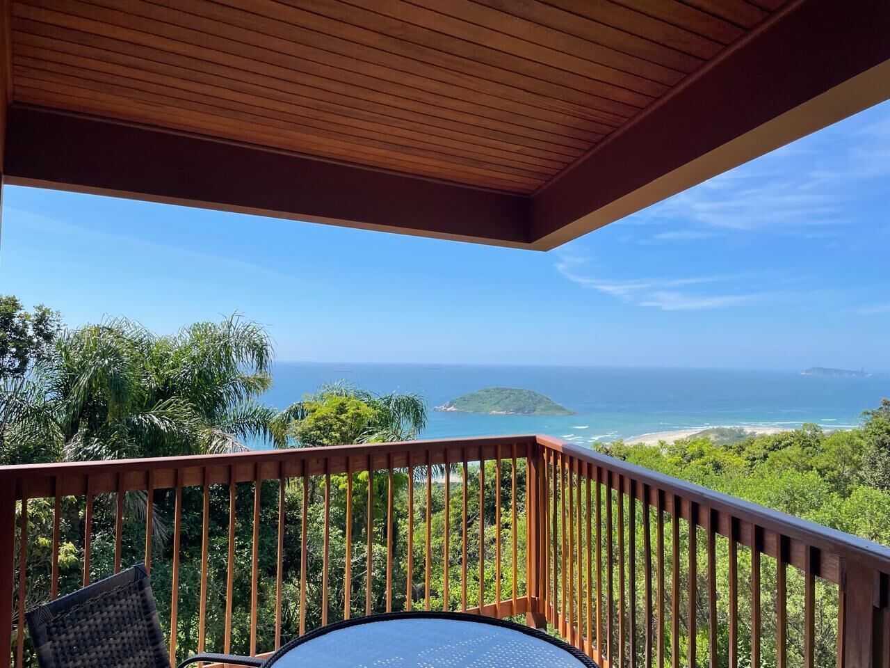 Una terraza de madera con vista al océano y una isla distante.