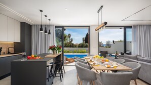 Une cuisine moderne avec un coin repas donnant sur une piscine.