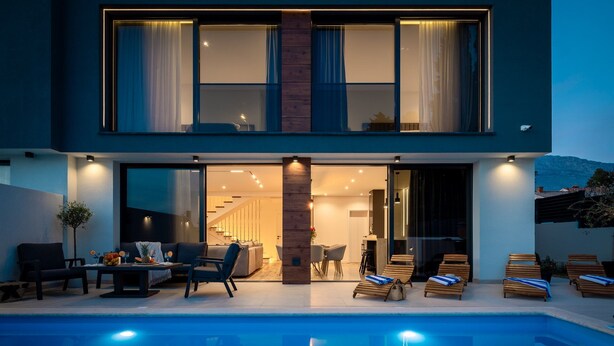 Une maison moderne à deux étages, dotée d’une piscine, d’un espace extérieur aménagé et d’un escalier menant à l’étage supérieur.