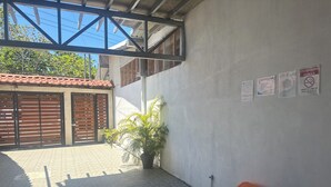 An outdoor area with a tiled floor, a potted plant, and trash bins.