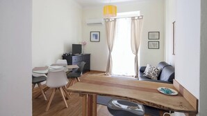A modern living room with a wooden dining table, a sofa, and a TV on a black cabinet. - The Traveler's House   (N. CITRA 011015-LT-1230) (La Spezia)