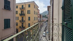 A narrow street with buildings on either side, a balcony with a metal railing, and a clear sky. - The Traveler's House   (N. CITRA 011015-LT-1230) (La Spezia)