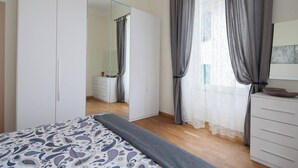 A bedroom with a bed, a wardrobe, a mirror, a dresser, and a window with curtains. - The Traveler's House   (N. CITRA 011015-LT-1230) (La Spezia)