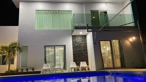 A modern two-story house with a swimming pool, glass balustrades, and outdoor seating. - Entire home with Pool. Walk to the beach. Lety Copel (Mazatlan)