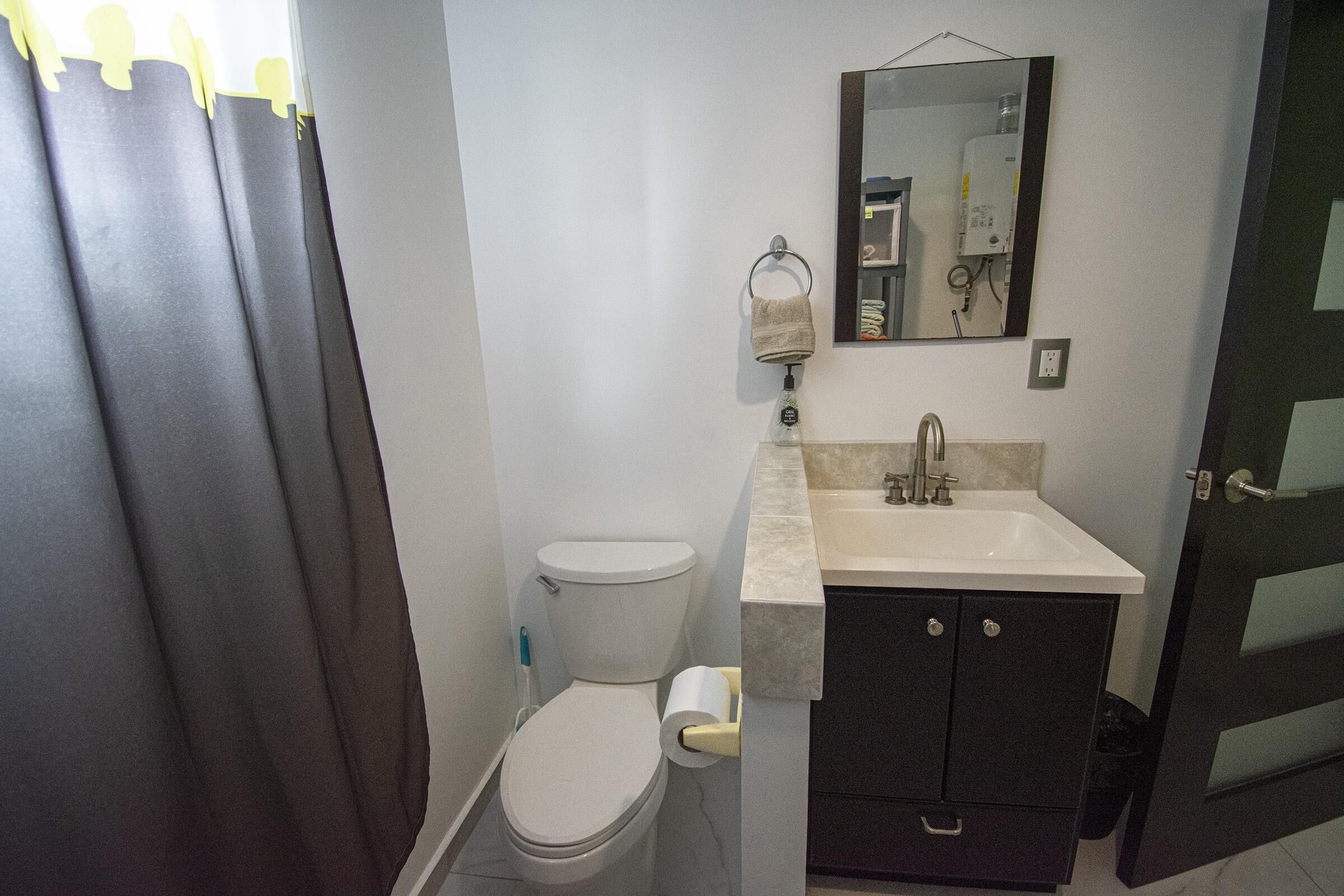 A bathroom with a toilet, sink, and cabinet.