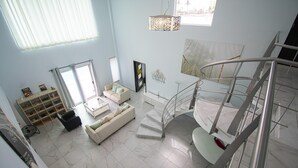 A spacious living area with a white sofa, a coffee table, and a staircase leading to an upper floor. - Entire home with Pool. Walk to the beach. Lety Copel (Mazatlan)