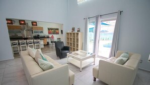 A spacious living area with a kitchen, two sofas, a coffee table, and a bookshelf. - Entire home with Pool. Walk to the beach. Lety Copel (Mazatlan)