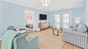 A living room with striped blue walls, a ceiling fan, a wooden cabinet, and a striped sofa. - 2nd Row, Beach Cottage, 3BR/2BA!  (Murrells Inlet)