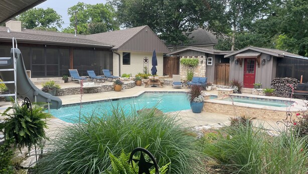 Ein Garten mit Swimmingpool, Liegestühlen und einer kleinen Gartenhütte.