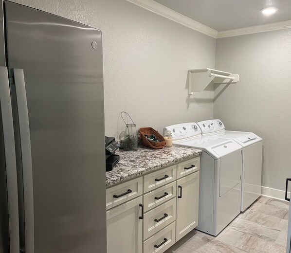 A compact laundry room with a stainless steel refrigerator, a washing machine, and a dryer.