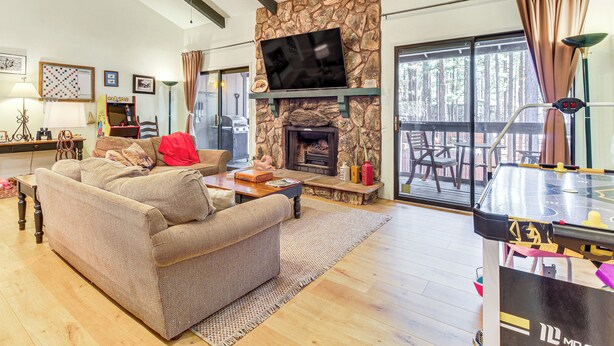 Una sala de estar acogedora con chimenea de piedra, televisor de pantalla plana y comedor con mesa de futbolín.