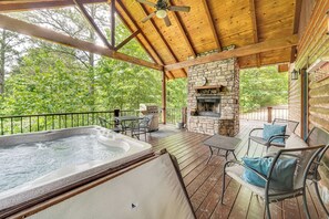 Una terraza techada al aire libre con jacuzzi, chimenea de piedra y mobiliario exterior.