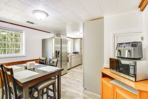 Eine kleine Küche mit Mikrowelle, Kühlschrank und einem Holzespeisetisch mit Stühlen.