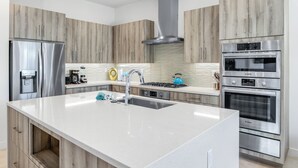 A modern kitchen with wooden cabinets, stainless steel appliances, and a central island.