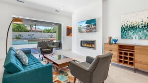 A modern living room with a sofa, armchairs, a coffee table, and a fireplace.