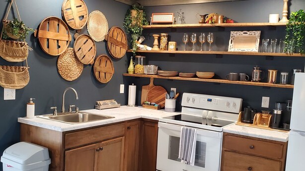 A kitchen with wooden cabinets, a white stove, and shelves with kitchenware.