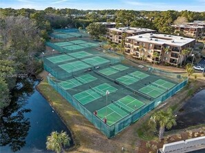 A tennis court complex with multiple courts, surrounded by residential buildings and a body of water. - Hilton Head Beach and Tennis resort located on Folly Beach. Steps from the beach (Hilton Head Island)