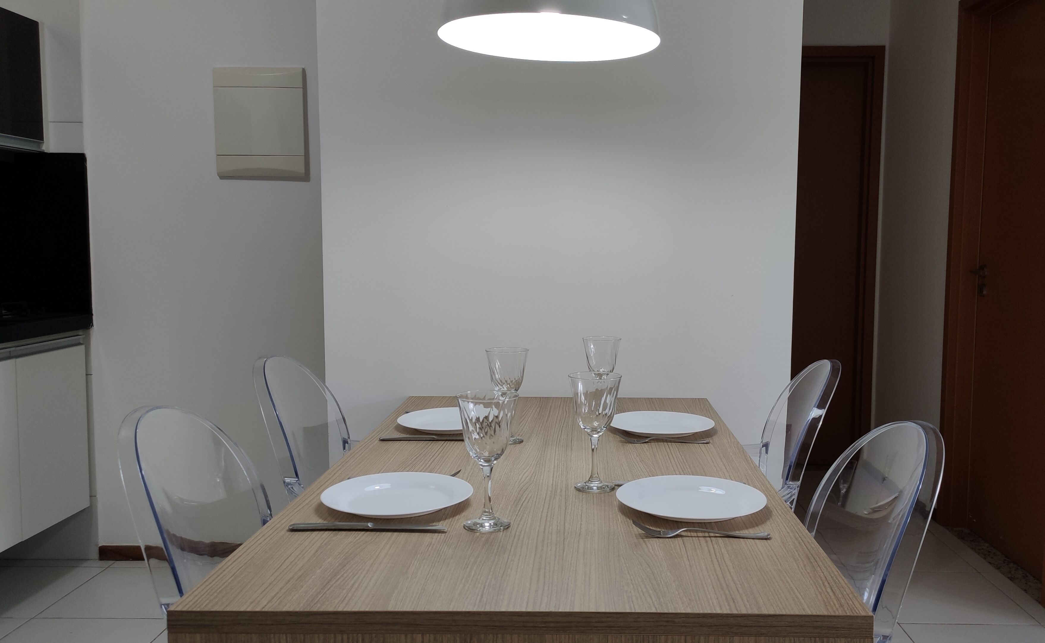 A dining table with four chairs, clear glassware, and white plates.