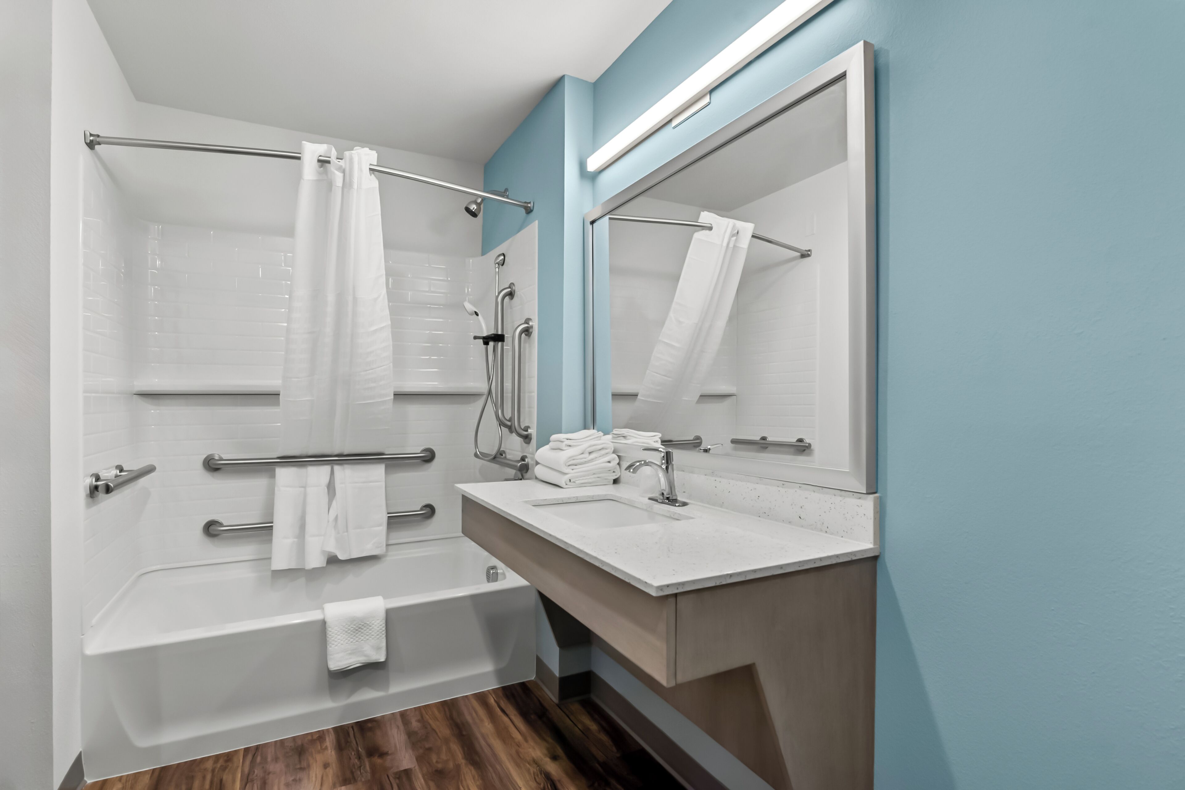 A modern bathroom with a bathtub, a sink, and a large mirror.
