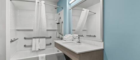 A modern bathroom with a bathtub, a sink, and a large mirror.