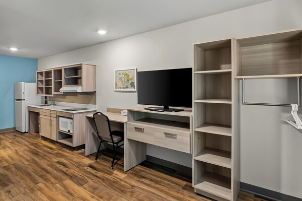 Una cocina moderna con estufa integrada, comedor con una silla y un amplio estante abierto.