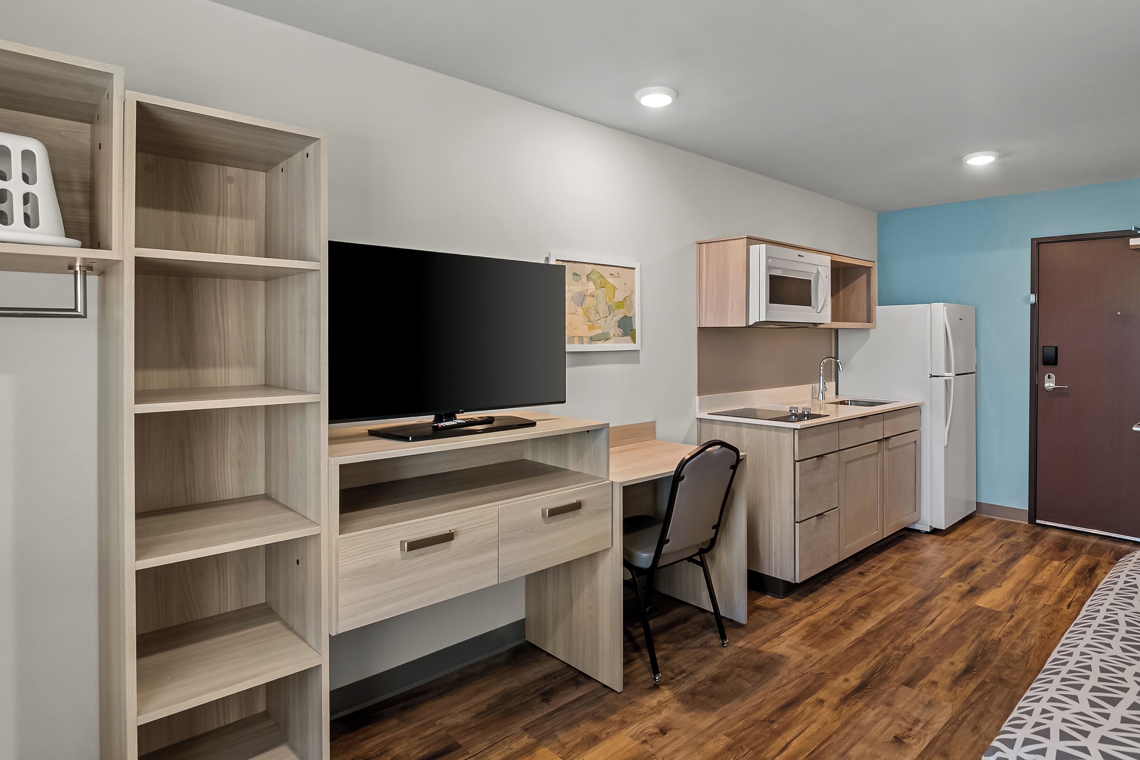 A modern kitchen with a wooden countertop, a built-in microwave, and a refrigerator.