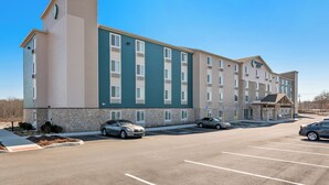 Un hôtel à plusieurs étages, doté d’une façade en pierre, de nombreux espaces de stationnement et surplombant un ciel d’un bleu éclatant.
