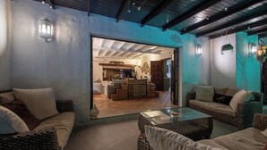 A cozy living area with wicker furniture, a glass coffee table, and a view into the kitchen. - Private quiet villa with a short walk to beaches, restaurants, bars and shops. (Tías)