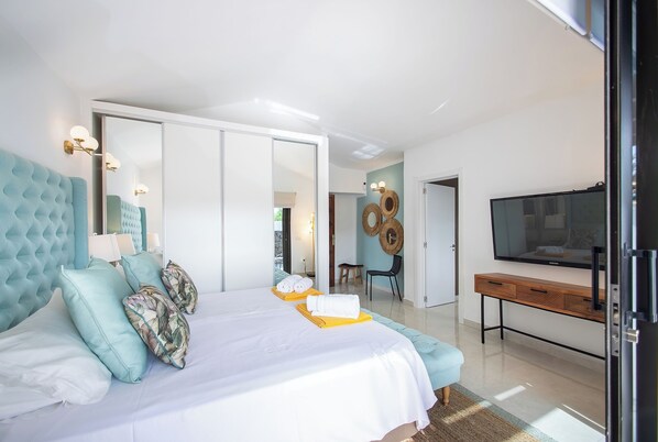Un dormitorio moderno con una cama grande, un televisor y una mesa consola de madera.