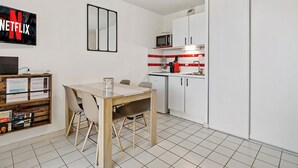 Une cuisine moderne avec des meubles blancs, un four à micro-ondes et un coin repas comprenant une table et des chaises.