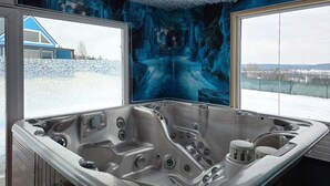 Ein modernes Badezimmer mit einer großen Badewanne, satinierten Glasfenstern und Blick auf eine verschneite Landschaft.