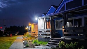 Eine Reihe moderner, gut beleuchteter Holzhütten mit Holzdecks und Außenbeleuchtung.
